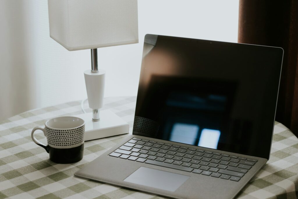 Laptop, mug, and lamp on a checkered tablecloth in a home setting