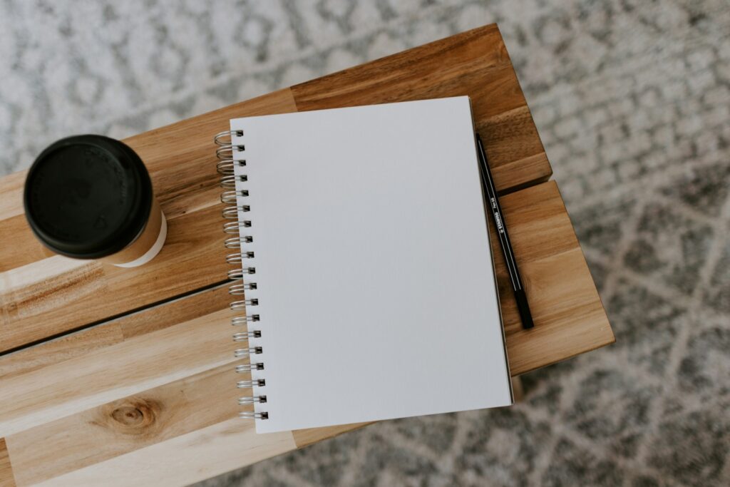 Open notebook and pen on a wooden bench