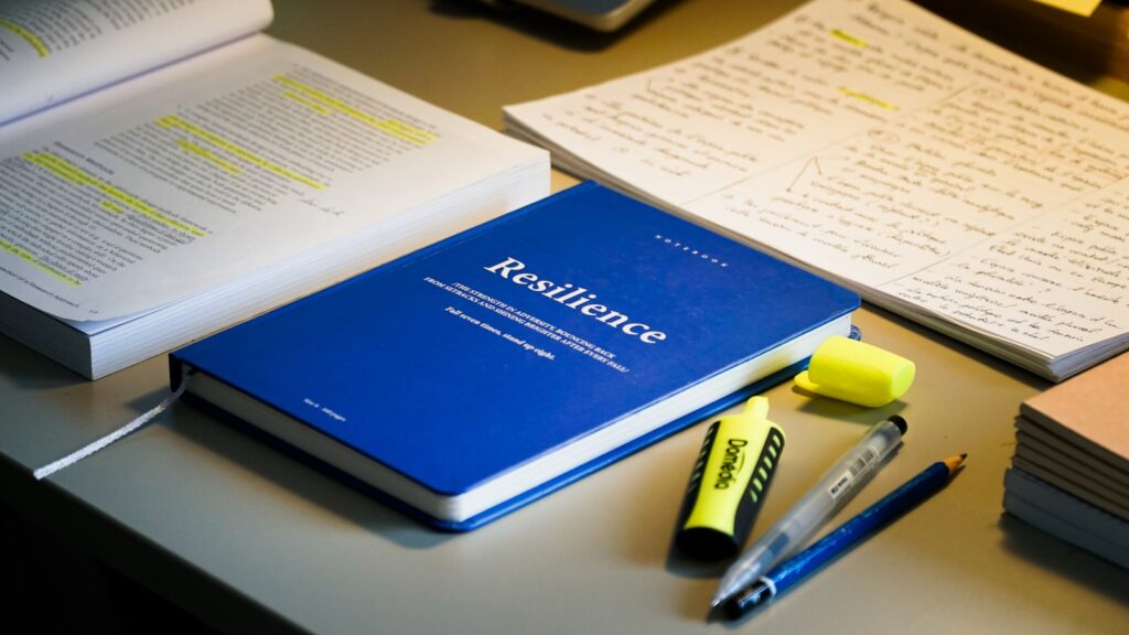 open textbook with study materials, pencils, and markers arranged on a wooden desk