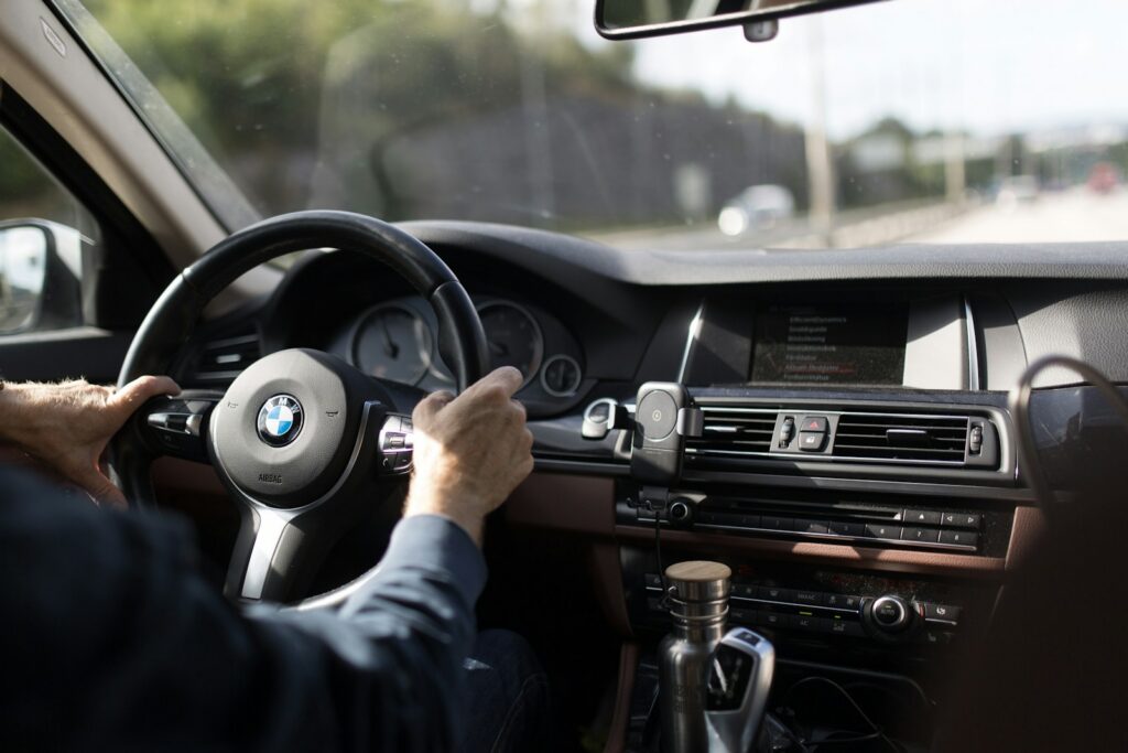 A driver's hands gripping a car steering wheel while driving