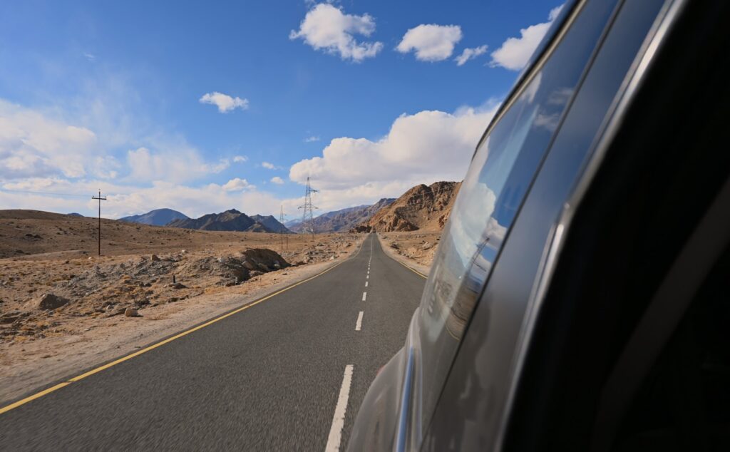 A car driving down a desert road with mountains in the background