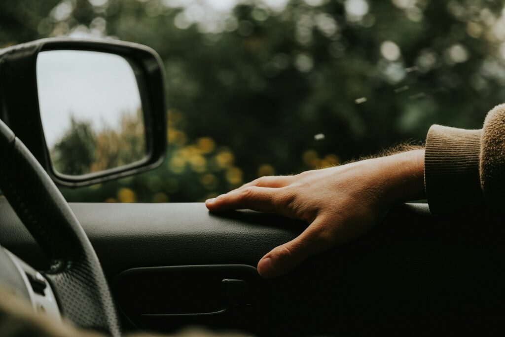 A driver's hand resting on a car steering wheel