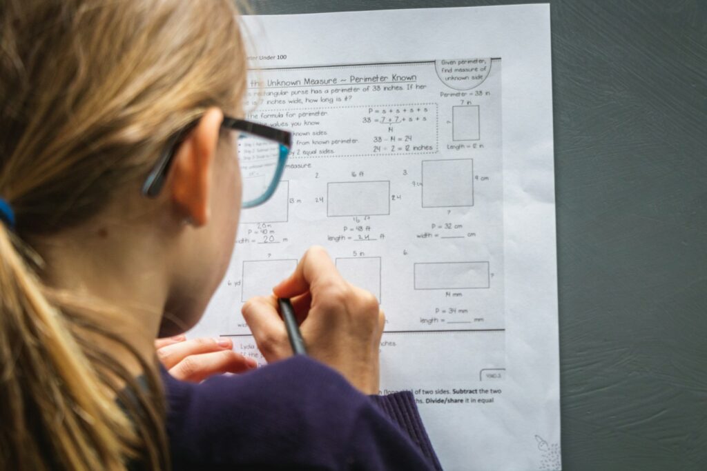 A student with glasses working on practice test questions from behind