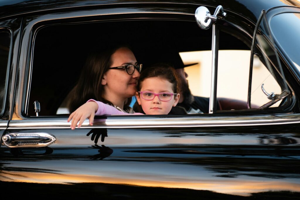 An adult supervising a young permit driver in the passenger seat of a car