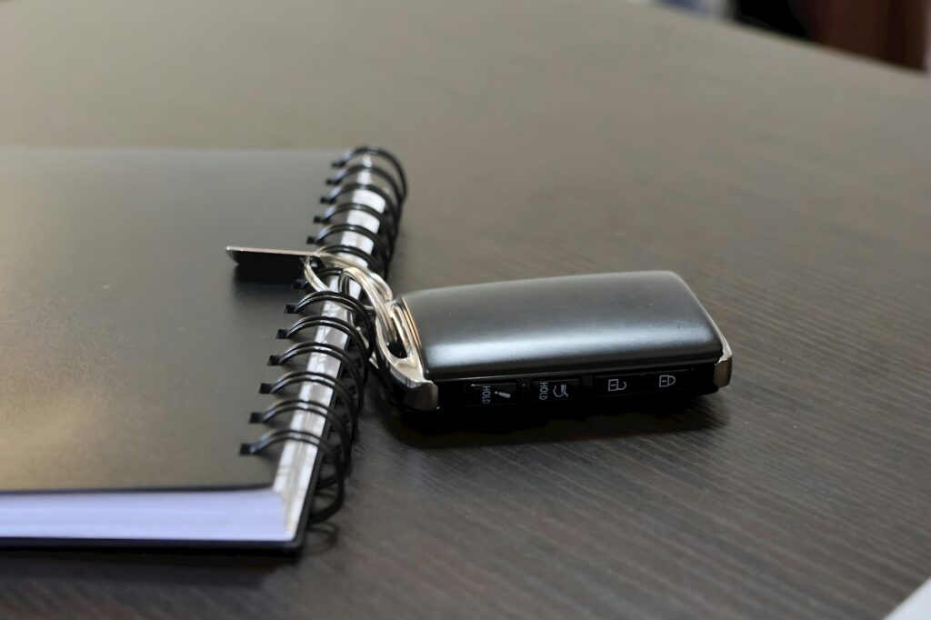 A car key lies next to a notebook on a desk