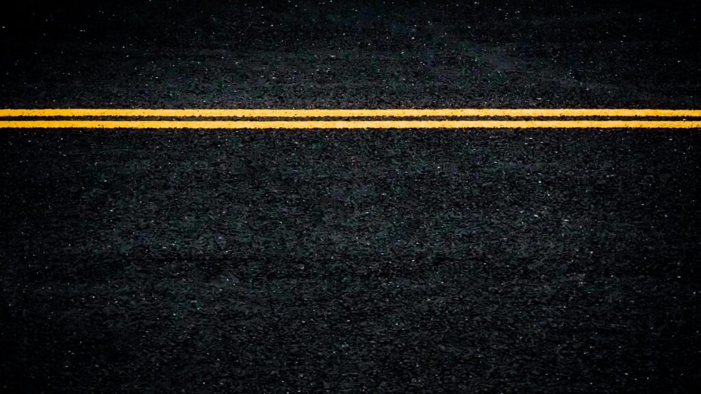 a black asphalt road with yellow line in the middle