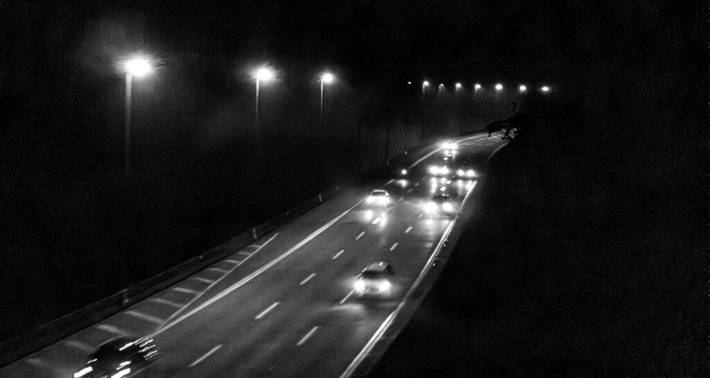 Cars with glowing headlights and taillights driving on a highway after dark