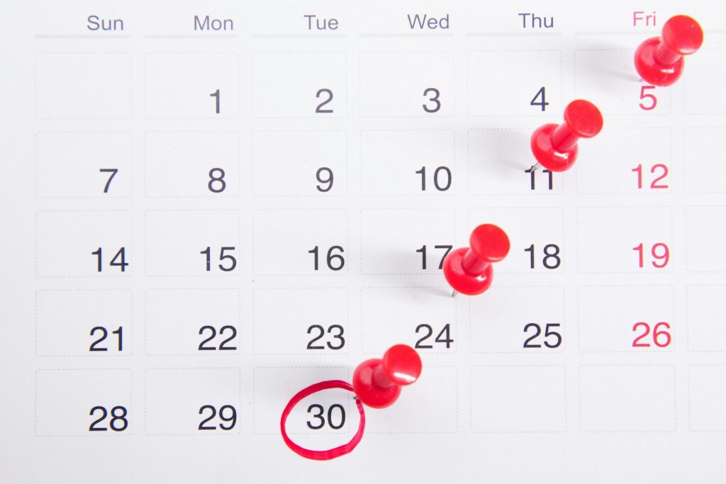A calendar with red push-pin markers tracking dates