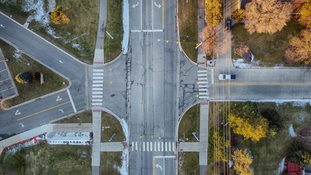 Aerial view of a four-way street intersection with vehicles approaching from each direction