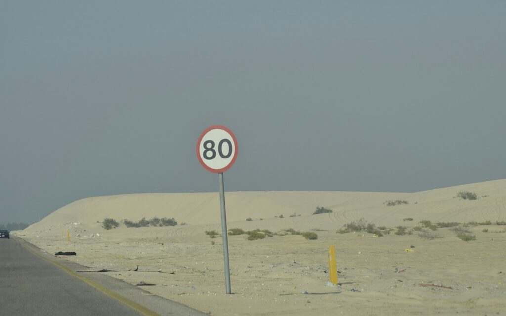 A speed limit sign reading 80 beside a desert highway