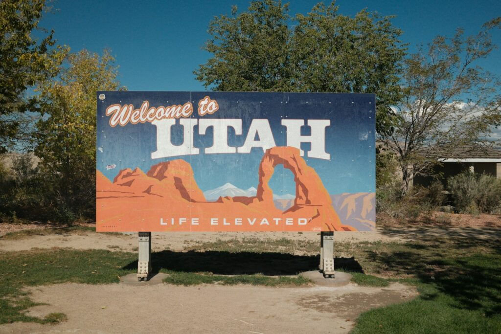 A Welcome to Utah road sign beside red rock desert landscape
