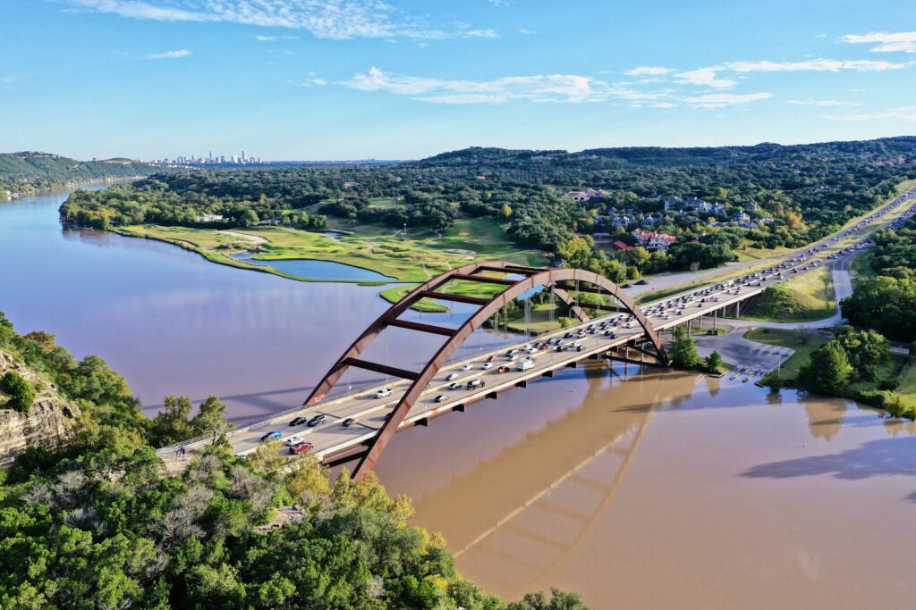 Cars driving across the Pennybacker Bridge with the Austin, Texas skyline in the background