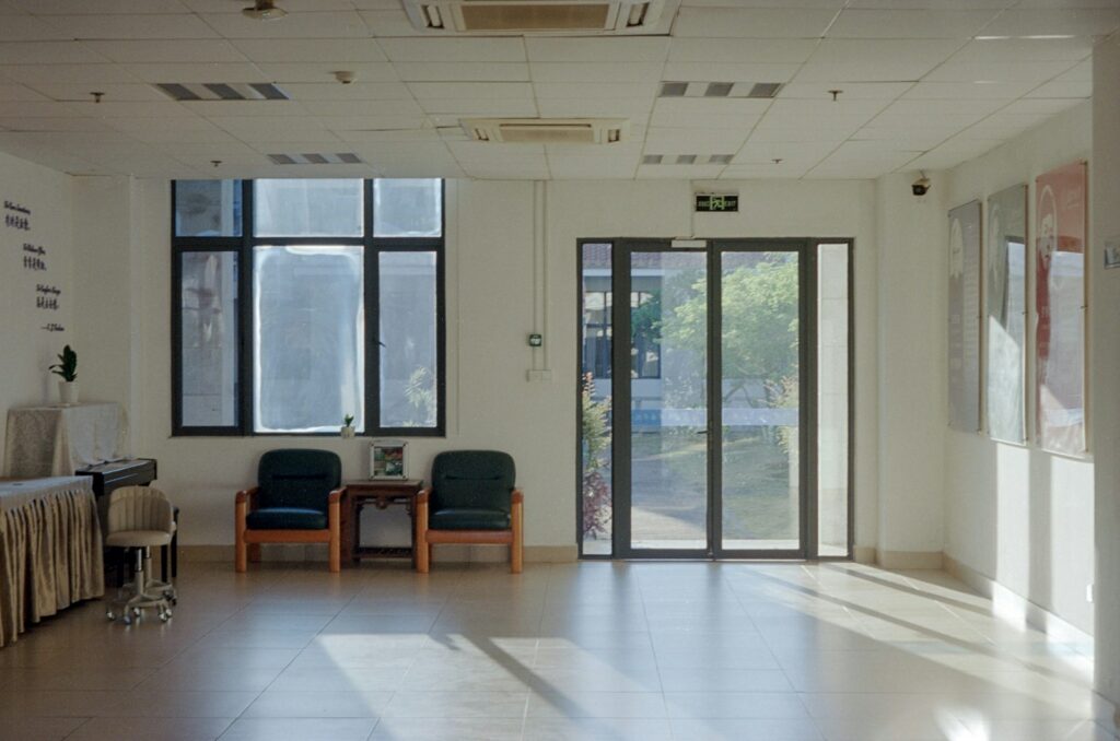 Sunlight streaming through windows into an empty waiting room lined with chairs