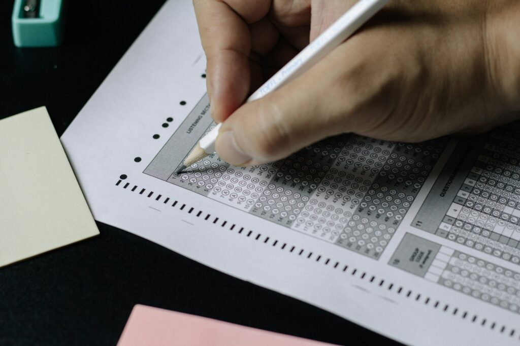 Hands filling in answers on a paper test with a pencil