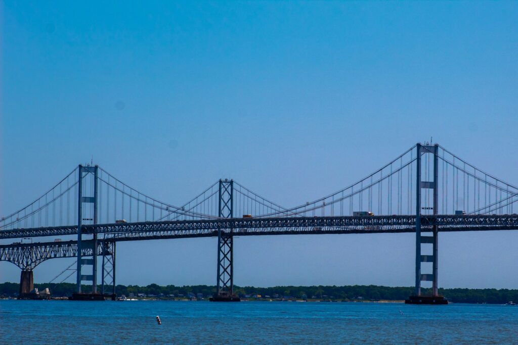 A dark bridge spanning open blue water under a clear sky