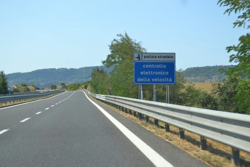 Speed limit sign posted along a highway under an open sky