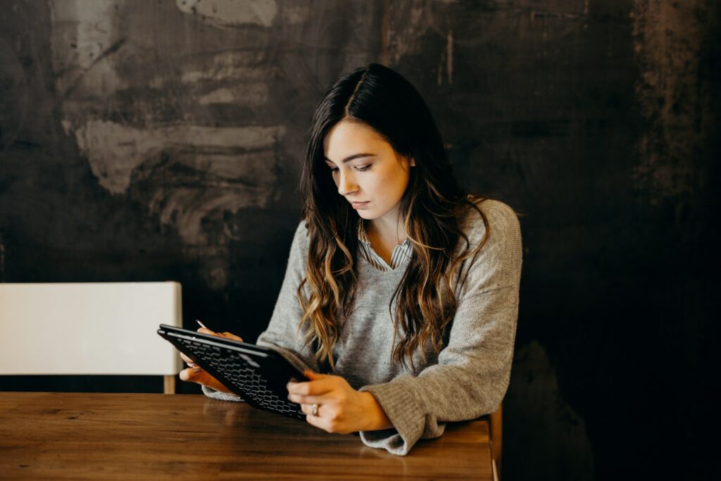 A person studying at a table, working through questions on a tablet with a stylus