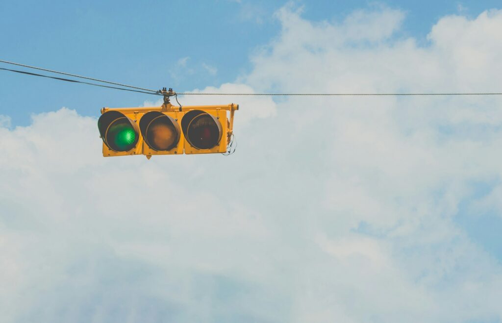 Overhead traffic signal head lit yellow against a pale sky