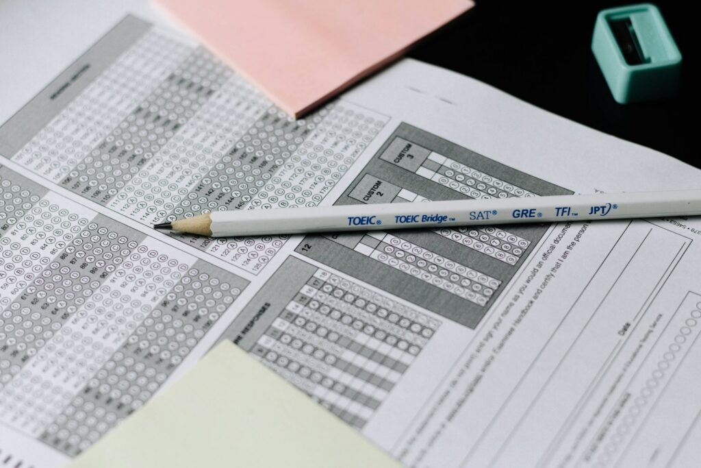 A yellow pencil resting on a bubbled multiple choice answer sheet beside pink sticky notes