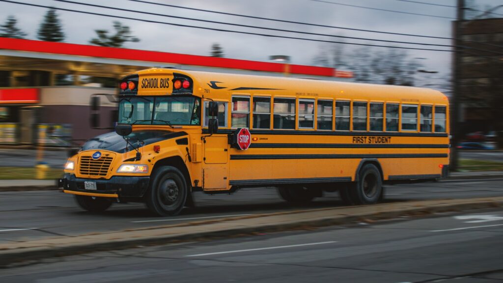 A yellow school bus driving down a street with motion blur
