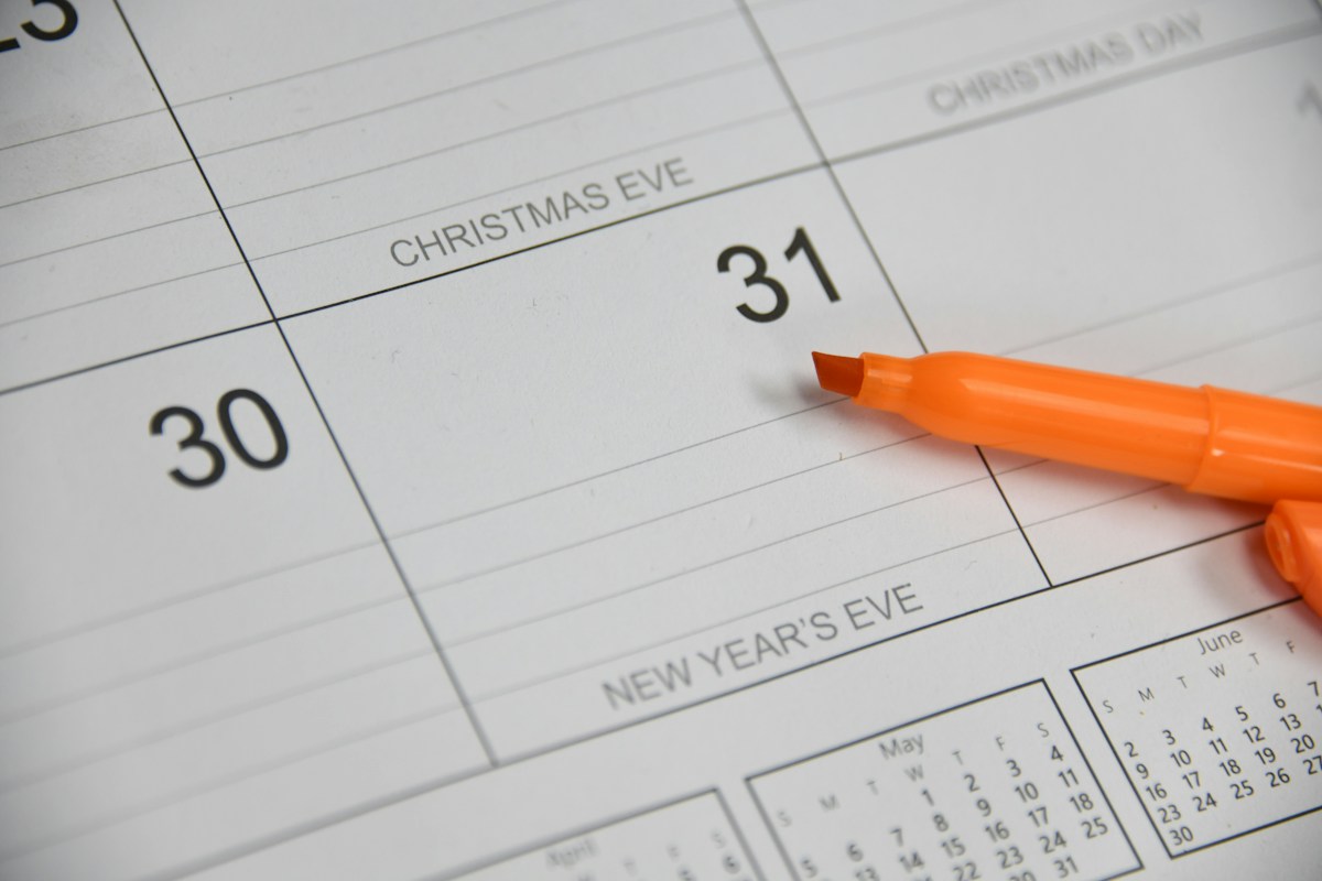 An orange highlighter resting on a wall calendar beside the numbers 30 and 31, the kind of date check a permit holder makes before an expiration deadline